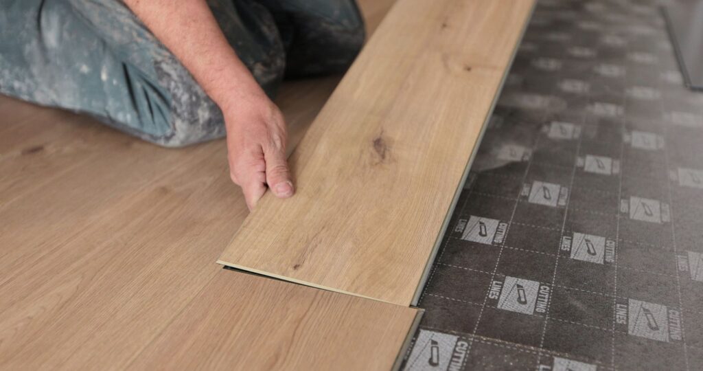renovation-construction-flooring-people-concept-closeup-man-installing-wooden-floor Polaganje laminata cena